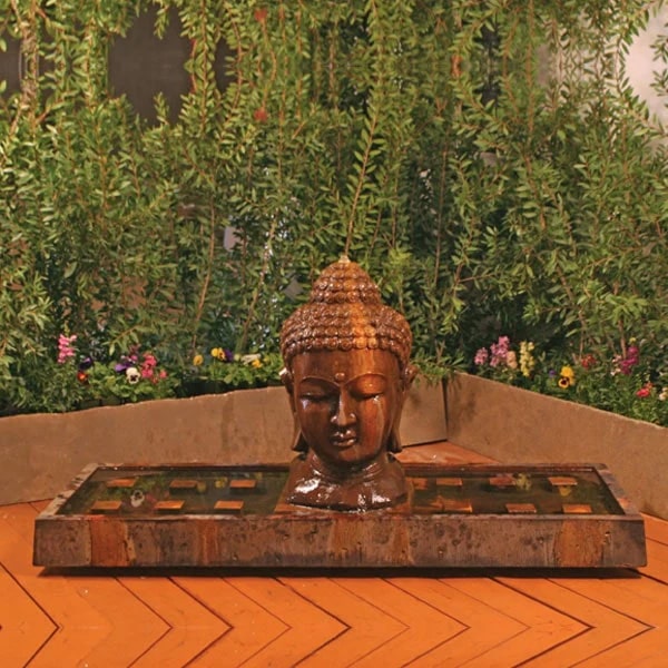 Buddha Water Fountains Collection Image of Buddha Head Fountain, Large against colorful flowers.