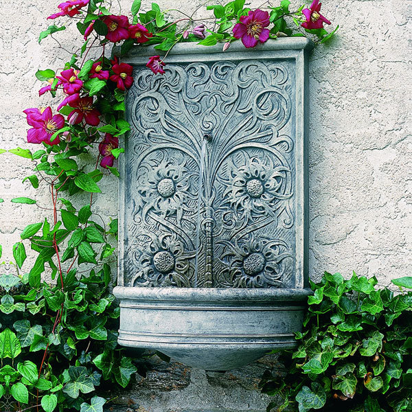 Outdoor Wall Fountain Collection Image of gray wall mountain fountain with flora details surrounded by ivy.
