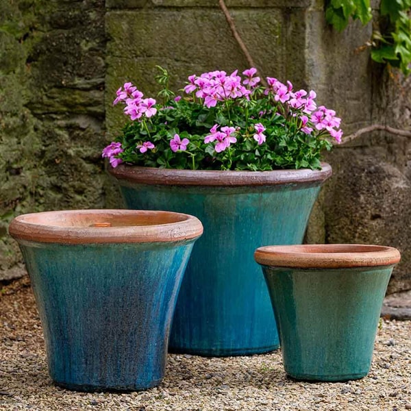 Tapered Planters Collection Image of Brighton Planter - Mediterranean - S/3 on gravel filled with pink flowers.