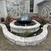 Crystal Sphere Fountain Kit installed in round stone bed with colorful flowers in front of home with stone exterior