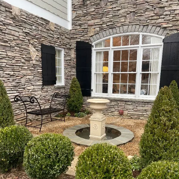 Palazzo Urn Fountain beside window surrounded with plants